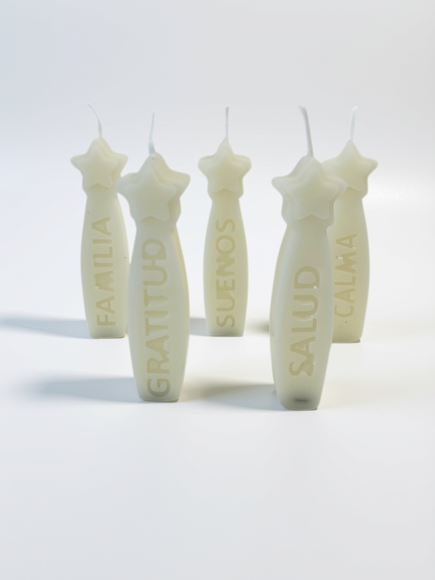 Velas Deseos CHIE: cinco velas navideñas de cera de soya en tono marfil, con estrella y palabras en relieve.