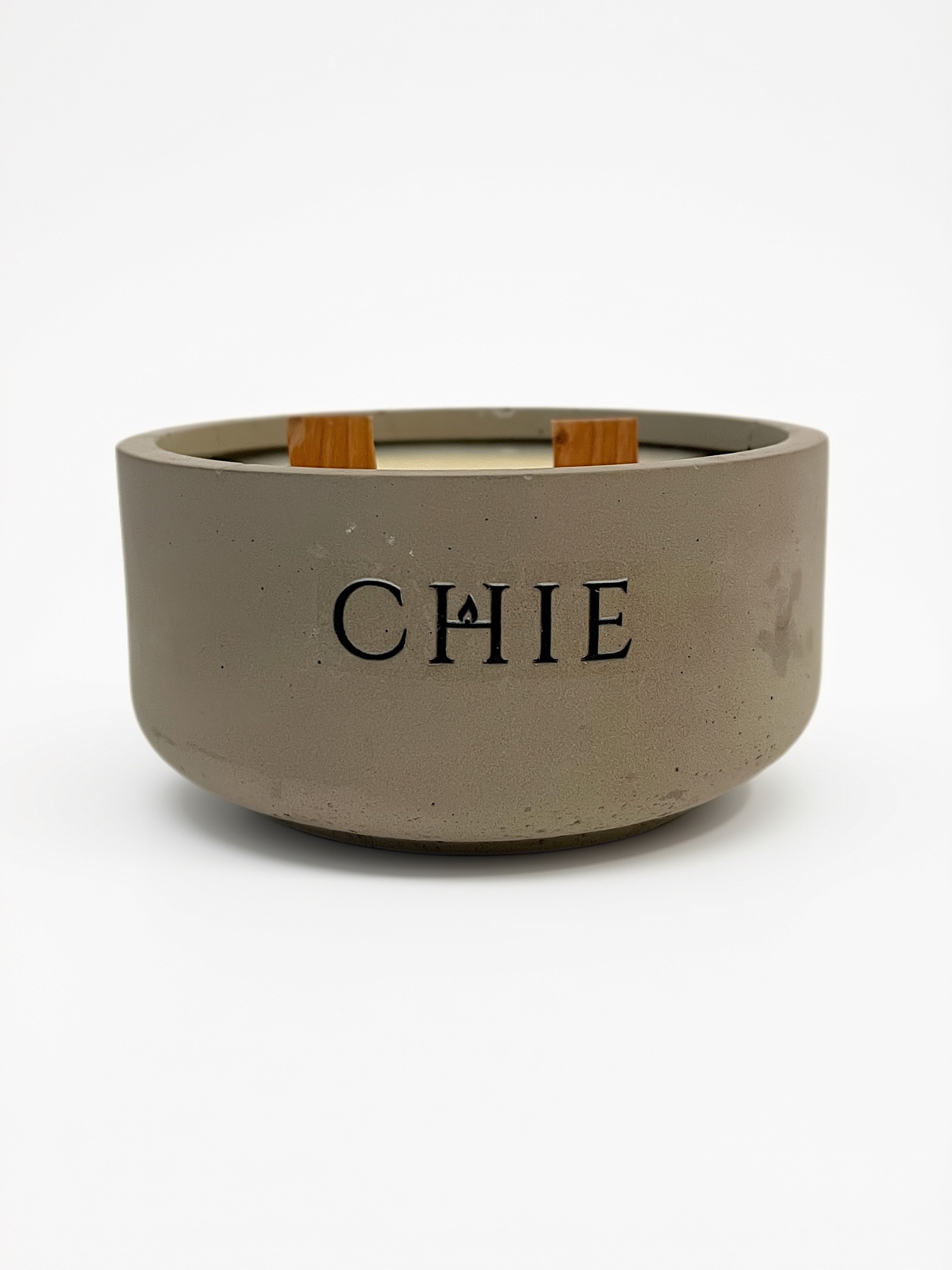 Vela aromática CHIE Verde Infinito de 200 g en envase de cemento con logo CHIE y dos pabilos de madera.