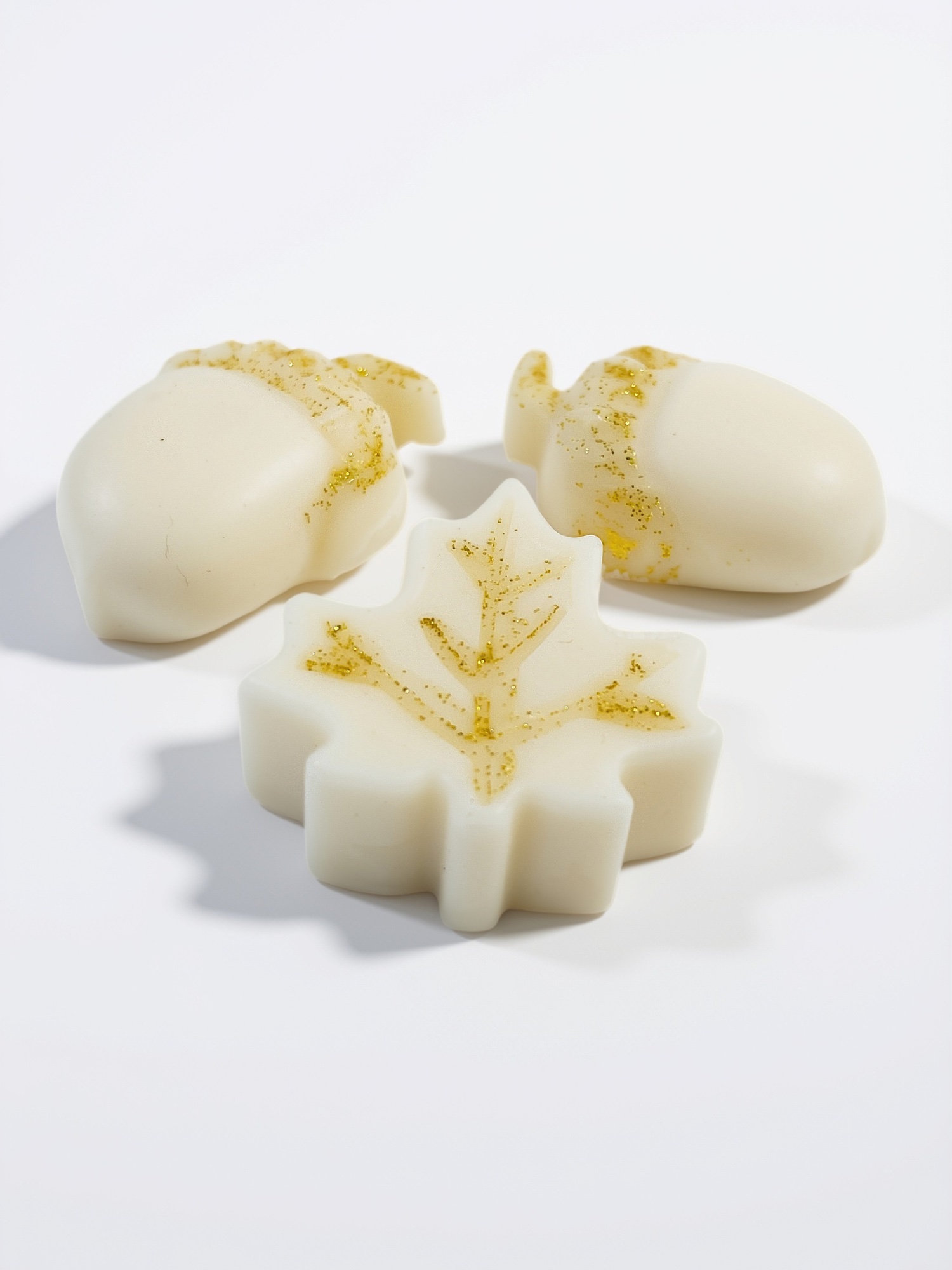 Wax melts CHIE Hoja & Nuez, aroma Bosque Navideño: dos bellotas y una hoja de arce en cera marfil con destellos dorados.